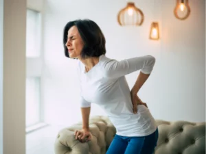 A woman with a pained expression, holding her back.