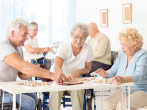 Elderly people sat around a table, while nejoying playing a board game.