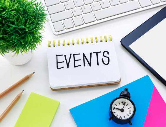 A graphic with a notebook surrounded by general office equipment (laptop, pencils, pot plant). On the notebook, is the label "Events"