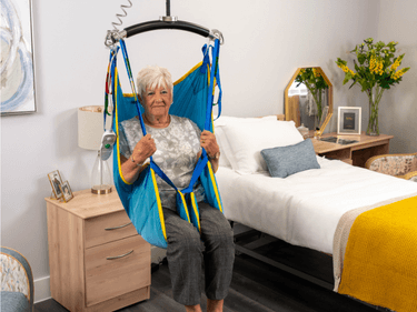 CA701 parasilk lifestyle (1) Lady being hoisted in a Care-ability CA701 sling with a ceiling track hoist.